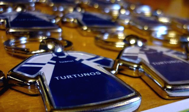 Varios llaveros metálicos con forma de camiseta, con el nombre del equipo, recién terminados